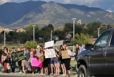 Students protest outside of Ralston Valley High School, as a motorist passes by, Tuesday, Sept. 23, 2014, in Arvada, Colo. The students are protesting a proposal by the Jefferson County School Board to emphasize patriotism and downplay civil unrest in the teaching of U.S. history. (AP Photo/Brennan Linsley)